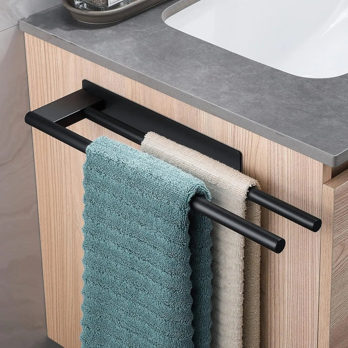 Black adhesive towel bar holding blue and gray towels