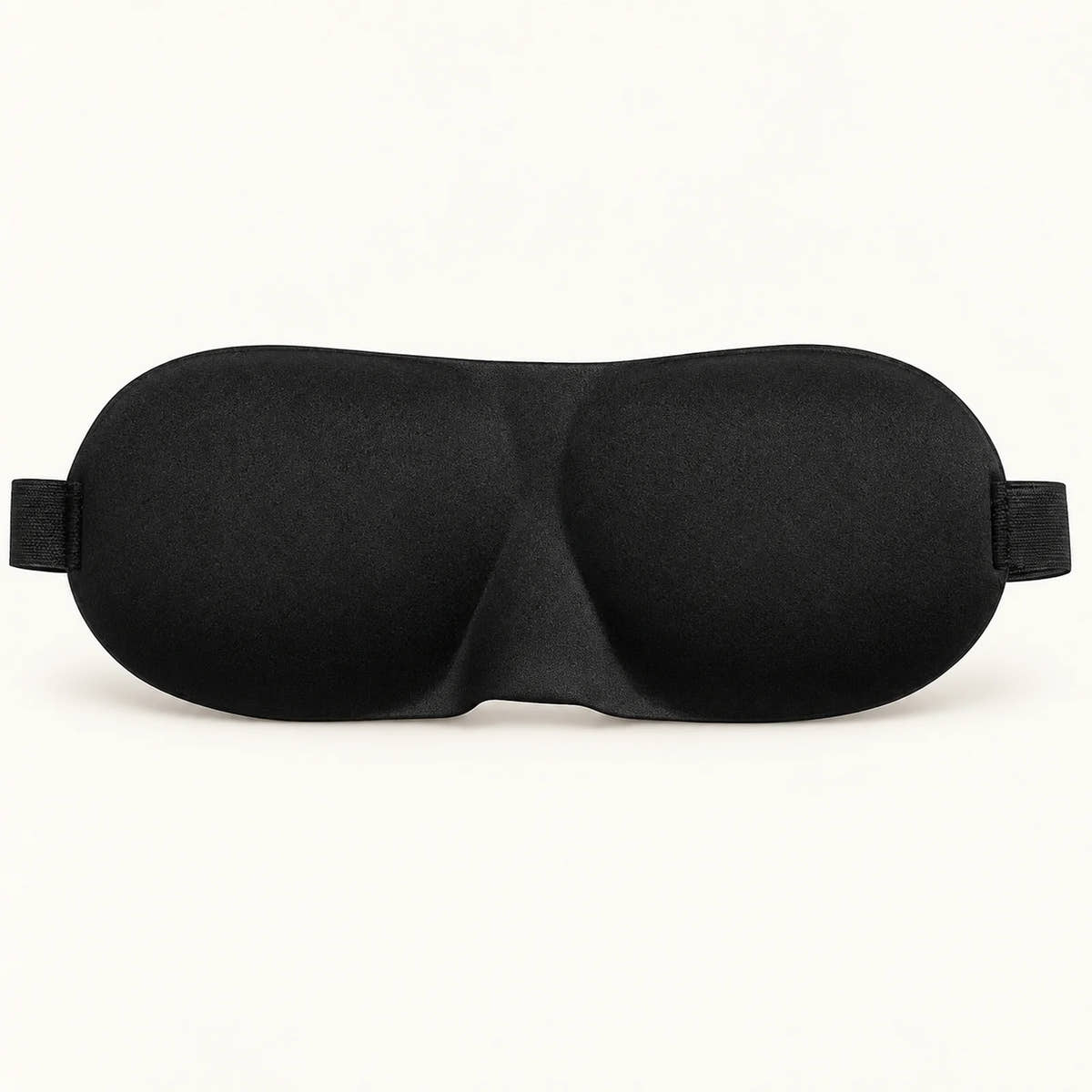 Black contoured sleep mask with molded eye cups and elastic strap ends.