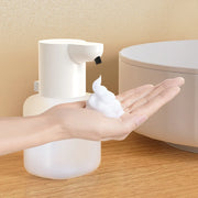 White touchless dispenser dispensing foam into a hand