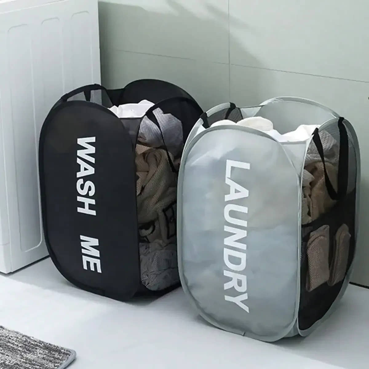 Black and gray pop-up mesh laundry hampers marked Wash Me and Laundry