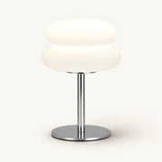 Bedside lamp with two rounded cream shade sections, chrome stem and round chrome base on an off-white background.