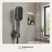 A matte black handheld shower head mounted on a wall in a modern bathroom setting, with a glass shower screen and window visible in the background. The Essentials House logo is shown at the bottom.