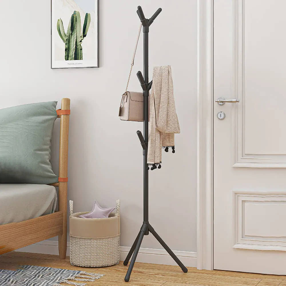 Black freestanding coat rack holding bags and clothing