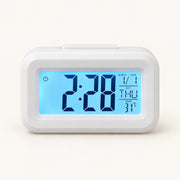 White digital desk alarm clock with blue backlit time, calendar and temperature display.