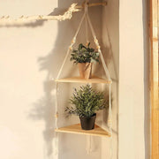 Three-tier macrame corner shelf holding small plants