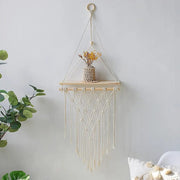 Diamond-shaped macrame wall shelf holding a small plant