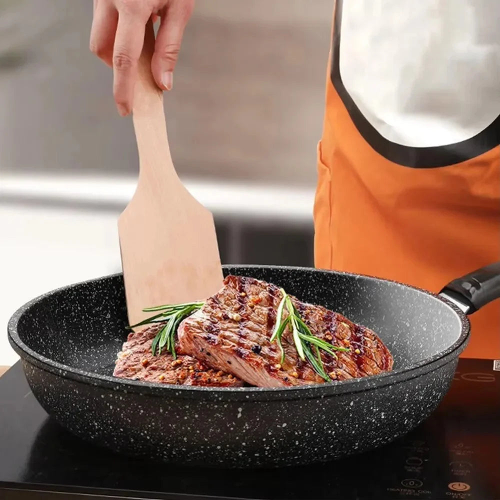 Stone-style nonstick frying pan cooking steak on a stovetop