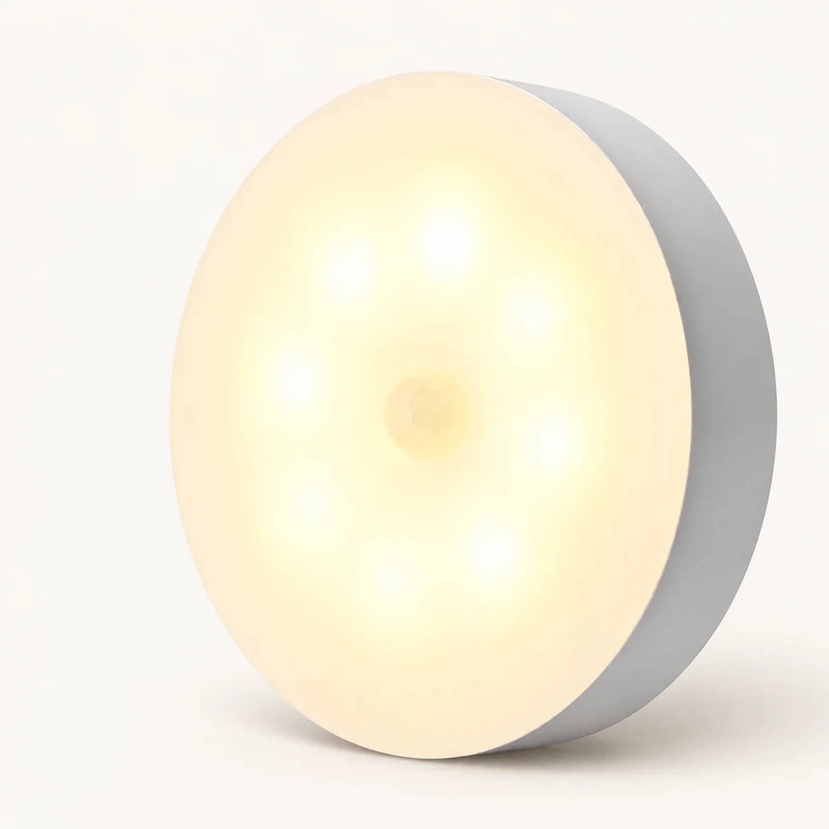 Single round warm-white motion sensor step light with a central sensor on an off-white background.