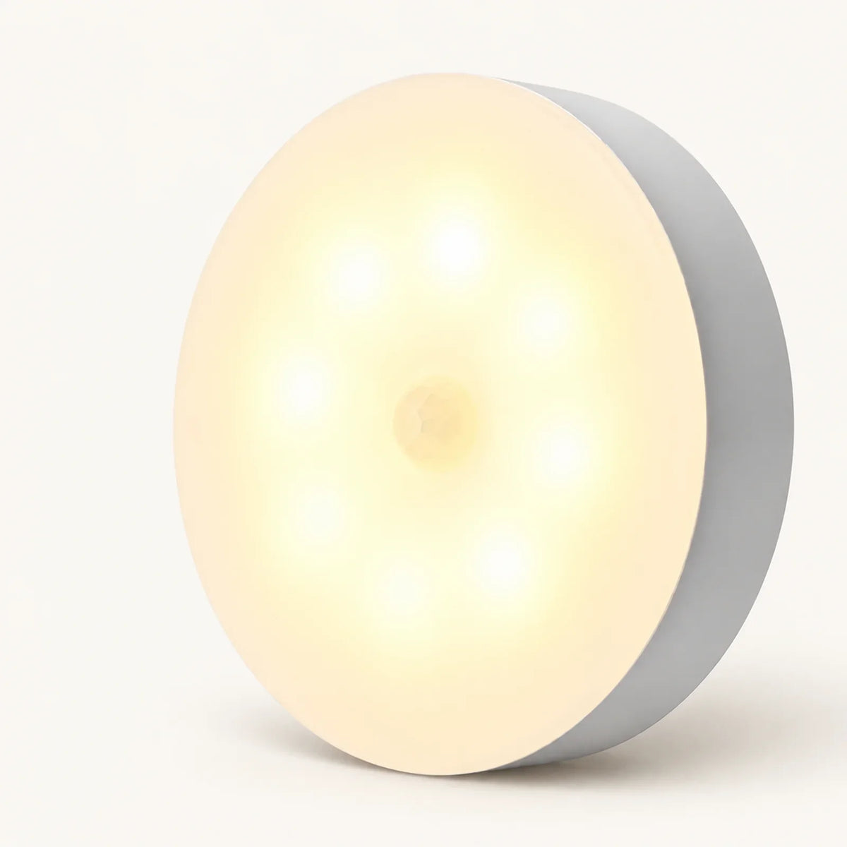 Single round warm-white motion sensor step light with a central sensor on an off-white background.