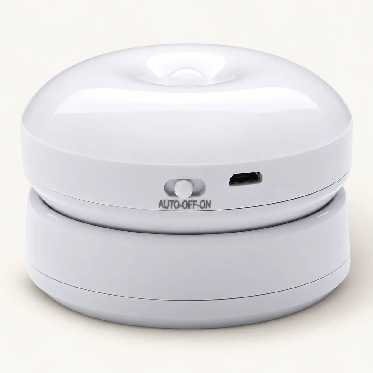 White round motion sensor wall light resting on its mount, showing slider switch and charging port on an off-white background.