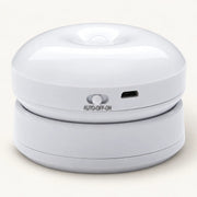 White round motion sensor wall light resting on its mount, showing slider switch and charging port on an off-white background.