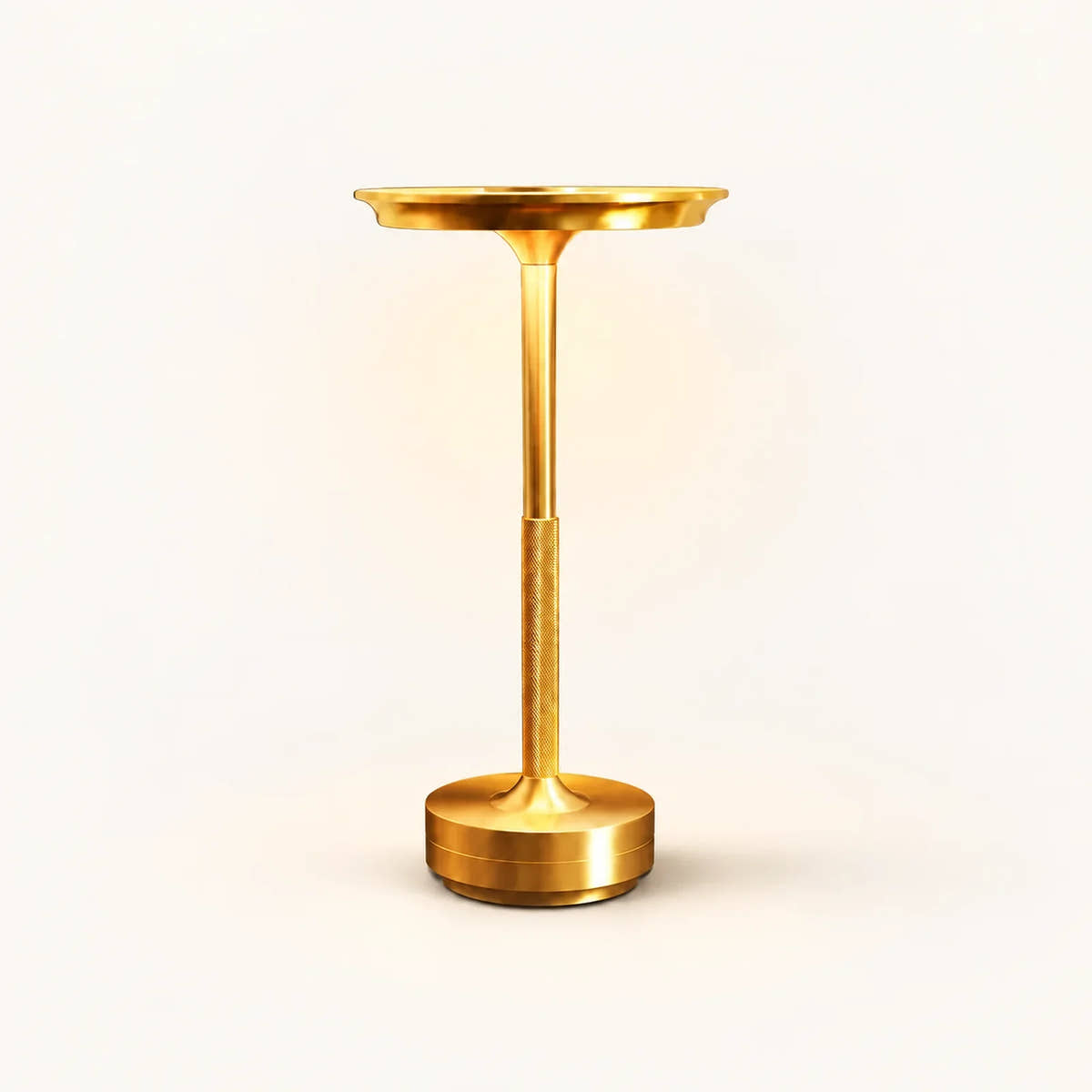 Gold rechargeable table lamp with shallow round shade, textured lower stem and cylindrical base on an off-white background.