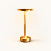 Gold rechargeable table lamp with shallow round shade, textured lower stem and cylindrical base on an off-white background.