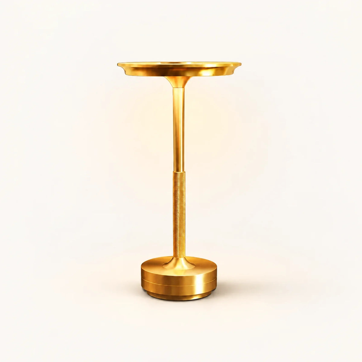 Gold rechargeable table lamp with shallow round shade, textured lower stem and cylindrical base on an off-white background.