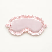 Light pink sleep eye mask with a satin finish, ruffled trim and gathered strap ends.