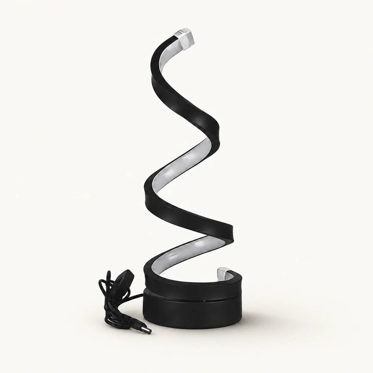 Black spiral LED lamp with silver inner diffuser, round base and coiled power cable on an off-white background.