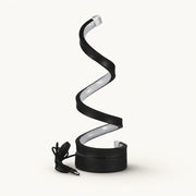 Black spiral LED lamp with silver inner diffuser, round base and coiled power cable on an off-white background.